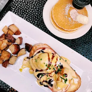 a plate of eggs benedict and potatoes