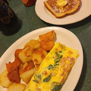 Ham and cheese omelet with spinach. Fried potatoes and French toast slice on homemade bread