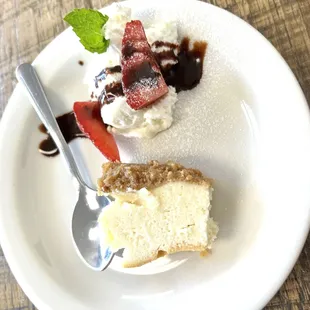 piece of cheese cake with a dab of whip cream, strawberry slices drizzled with chocolate.