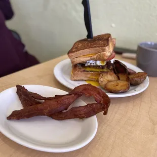 two plates of bacon and a sandwich