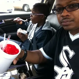 a man sitting in a car with a cup of ice cream