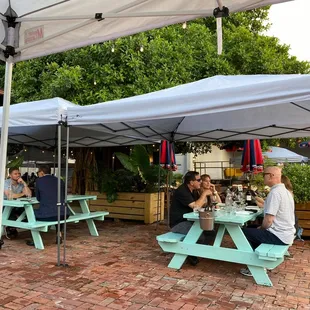 people sitting at picnic tables under umbrellas