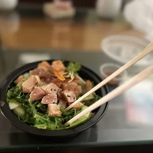 a bowl of sushi with chopsticks