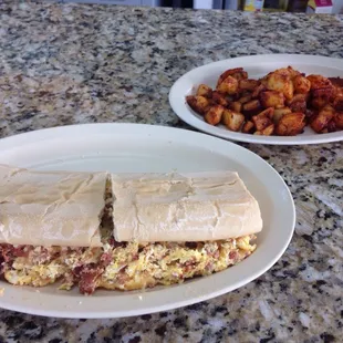 Sausage egg and cheese sandwich on Cuban bread with a side of home fries