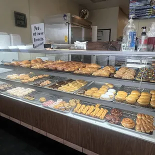 Donut display case with croissant and beer rocks on the top shelf