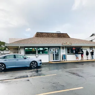a blue car parked in front of a restaurant