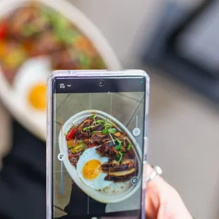 a person taking a picture of a plate of food