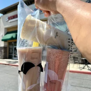a hand holding two cups of iced tea