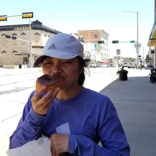 a woman eating a doughnut on a city street