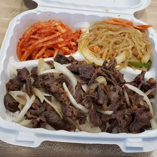 a takeout box with a variety of food items