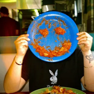 a man covering his face with a plate of food