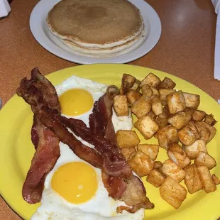 Sunny side up eggs, bacon, and home fries, and pancakes