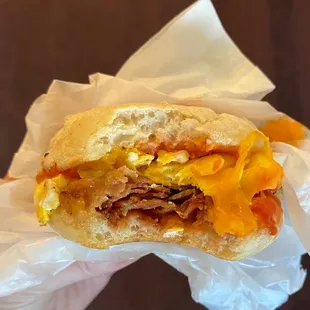 Egg, bacon, and cheddar sandwich, on an English muffin, with ketchup added.