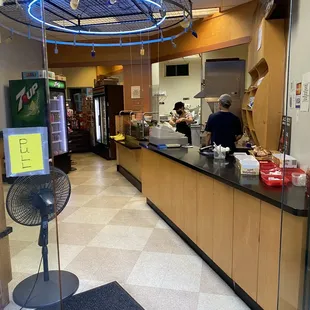a restaurant counter with a fan in the foreground
