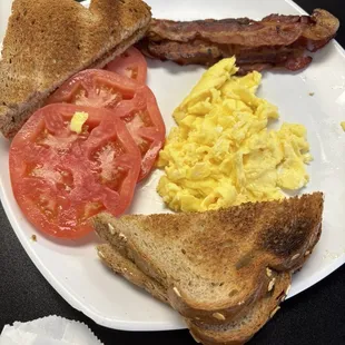 Scrambled eggs, tomatoes, bacon and whole wheat toast