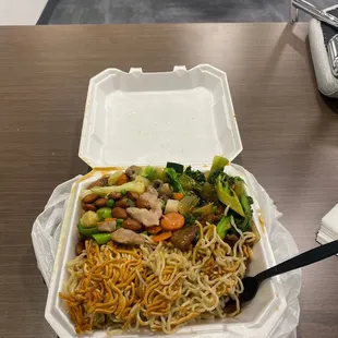 a take out container of noodles and vegetables