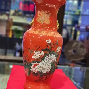 a red vase with flowers on it
