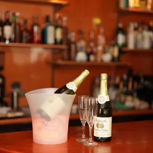 a bottle of champagne and two glasses on a bar