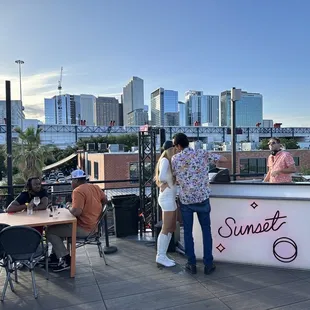 two people standing at a bar with a view of the city