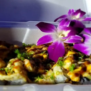 a purple flower on top of a sushi