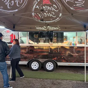 a man and a woman standing in front of a food truck