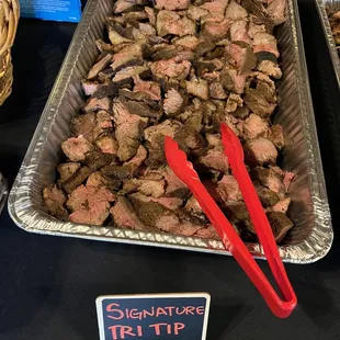 two trays of meat with tongs