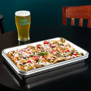 a tray of nachos and a pint of beer