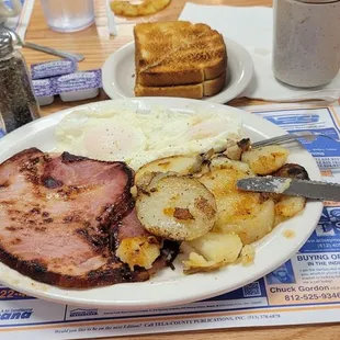 2/10/24 one of my favorite breakfasts here The ham steak two eggs over easy. Home fries on the grill white toast cawfee Yummers!