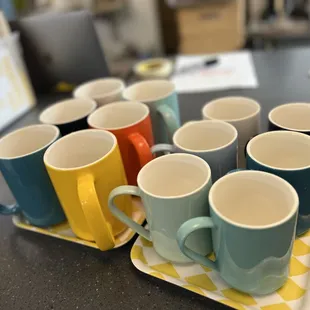 a row of coffee mugs on a tray