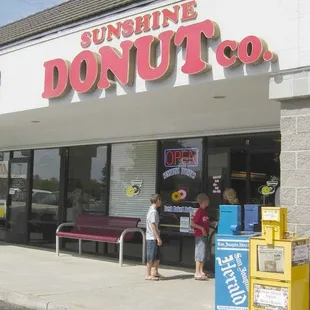 two children standing in front of a donut shop