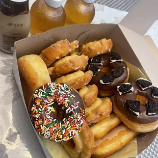 Some delicious donuts, Oreo cookie, old fashioned, sprinkles, maple and chocolate bars. Apple juice and coffee.