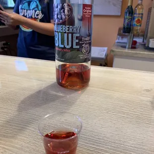 a bottle of blueberry wine and a shot of red wine