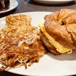 a croissant sandwich and hash browns