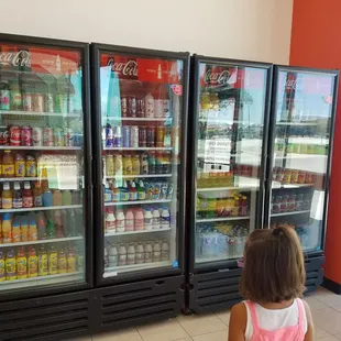 a little girl standing in front of a refrigerator