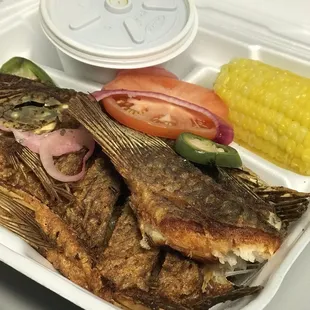 a tray with a fish and corn on the cob