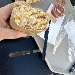 a person holding a sandwich on a tray
