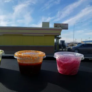 three cups of sauce on the dashboard of a car