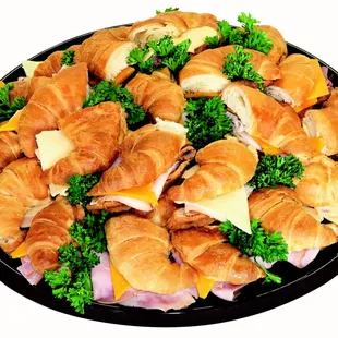 a platter of croissants, ham, cheese, and broccoli