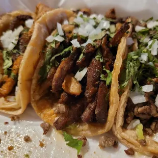 three tacos with meat and onions