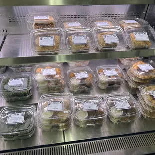 Cold case featuring falafel, tabouleh, meat pies, and baklava.