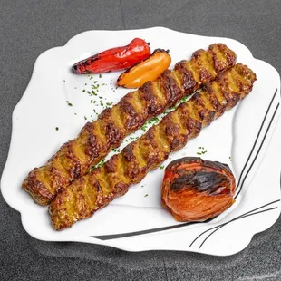 two skewers of meat on a white plate