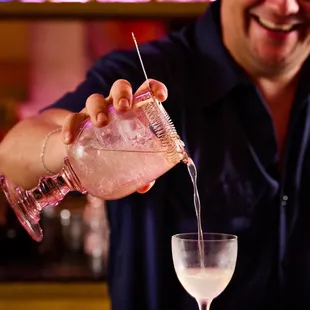 a man pouring a drink into a glass