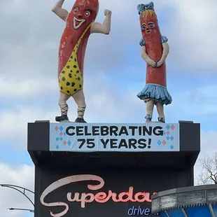 two hot dogs on top of a sign