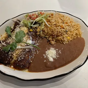 Pollo con Mole enchiladas with refried beans and Mexican rice..