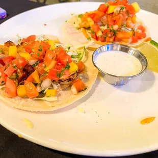 a plate of tacos with a side of salsa