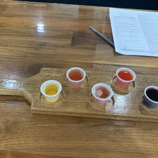 a wooden board with four small cups of sauce on it