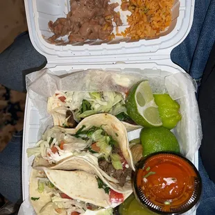 a takeout box with a variety of tacos and rice