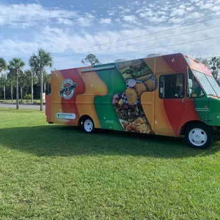 a colorful food truck parked in the grass