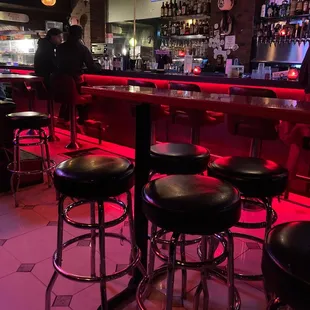 a bar with stools and a television in the background