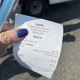 a person's hand holding a receipt